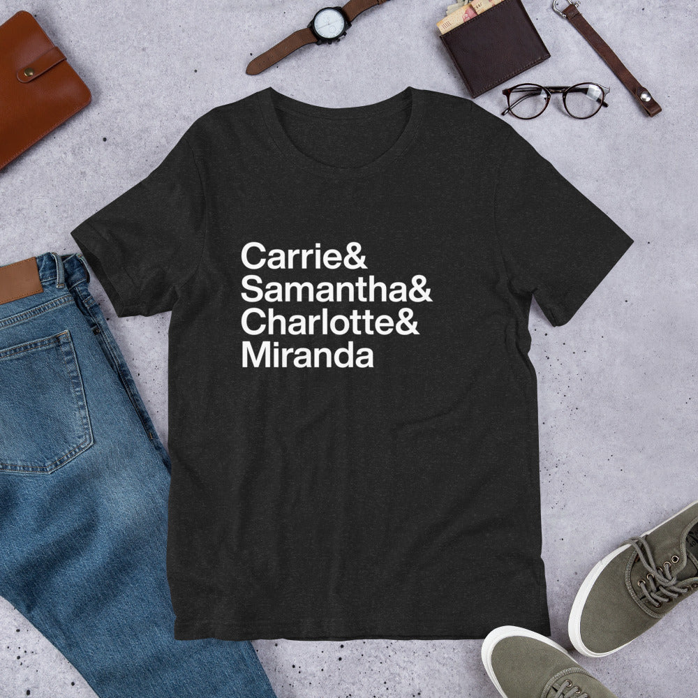 black t-shirt with white lettering reading Carrie and Samantha and Charlotte and Miranda on ground next to other clothing