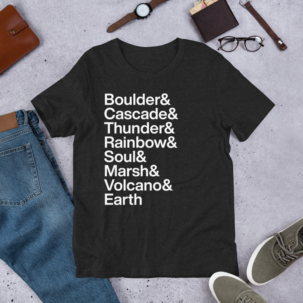black t-shirt with white lettering reading Boulder and Cascade and Thunder and Rainbow and Soul and Marsh and Volcano and Earth on ground amidst other apparel