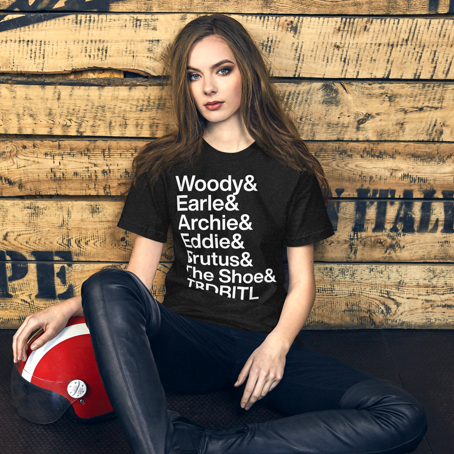Young woman on floor with AmpTee t-shirt reading "Woody and Earle and Archie and Eddie and Brutus and The Show and TBDBITL"