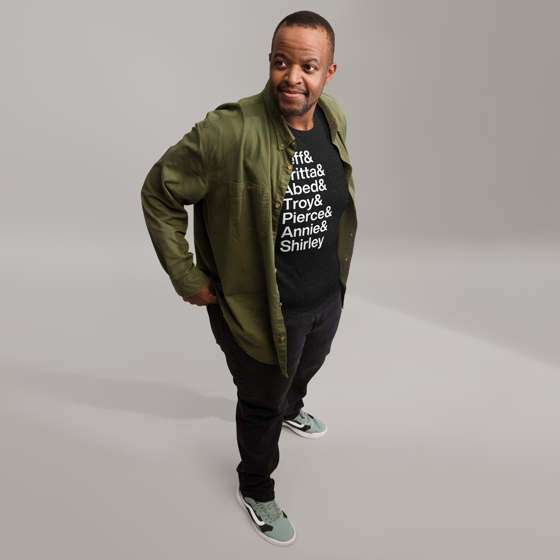Man in jacket with a black t-shirt with white lettering reading Jeff and Britta and Abed and Troy and Pierce and Annie and Shirley