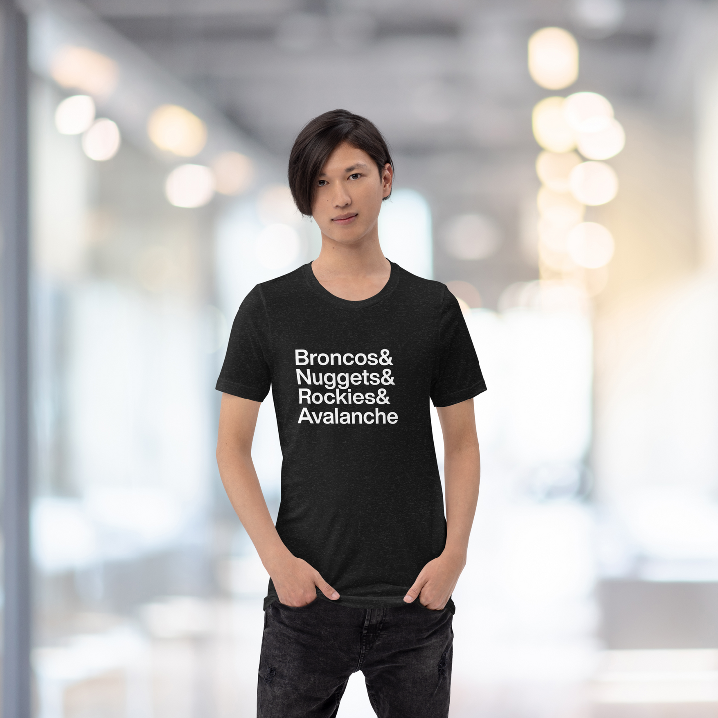 Young person in hallway wearing black t-shirt with white lettering reading Broncos and Nuggets and Rockies and Avalanche