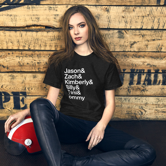 Young woman sitting on the ground wearing a black t-shirt with white lettering reading Jason and Zach and Kimberly and Billy and Trini and Tommy