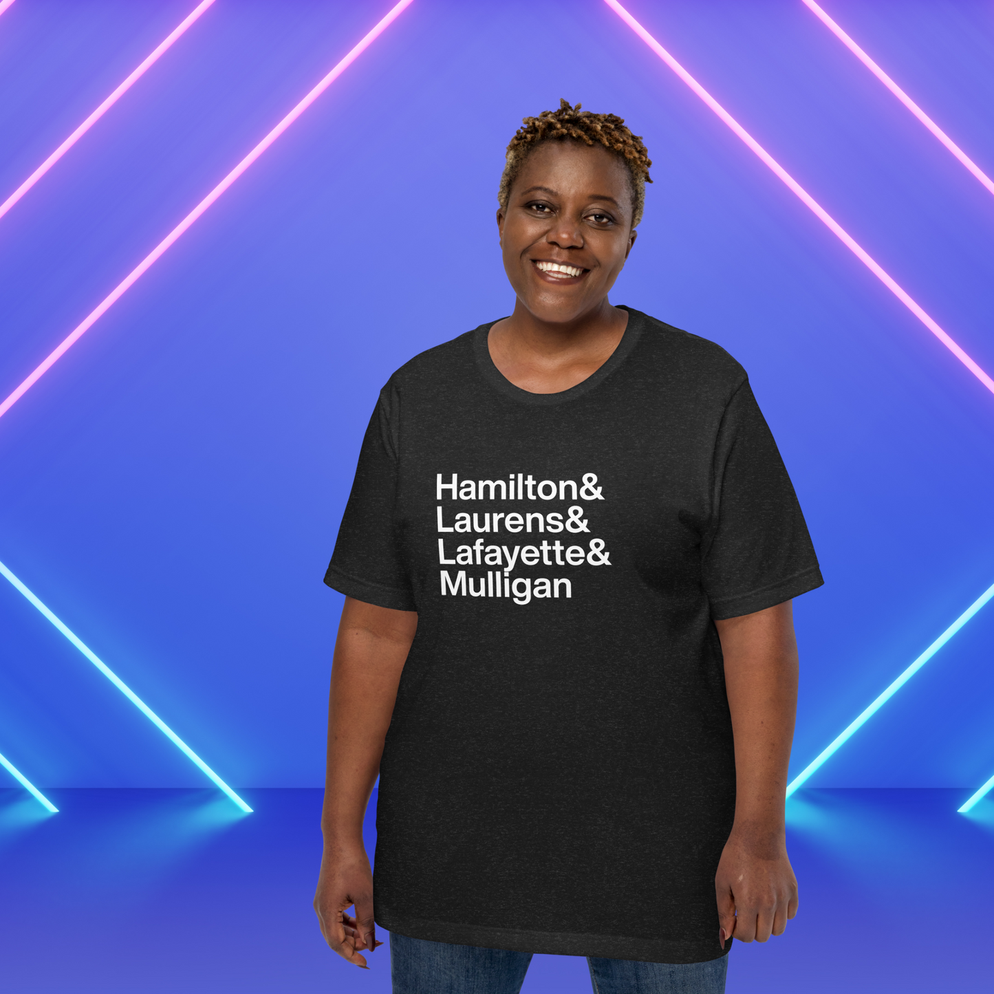 Woman under neon wearing black t-shirt with white lettering reading Hamilton and Laurens and Lafayette and Mulligan