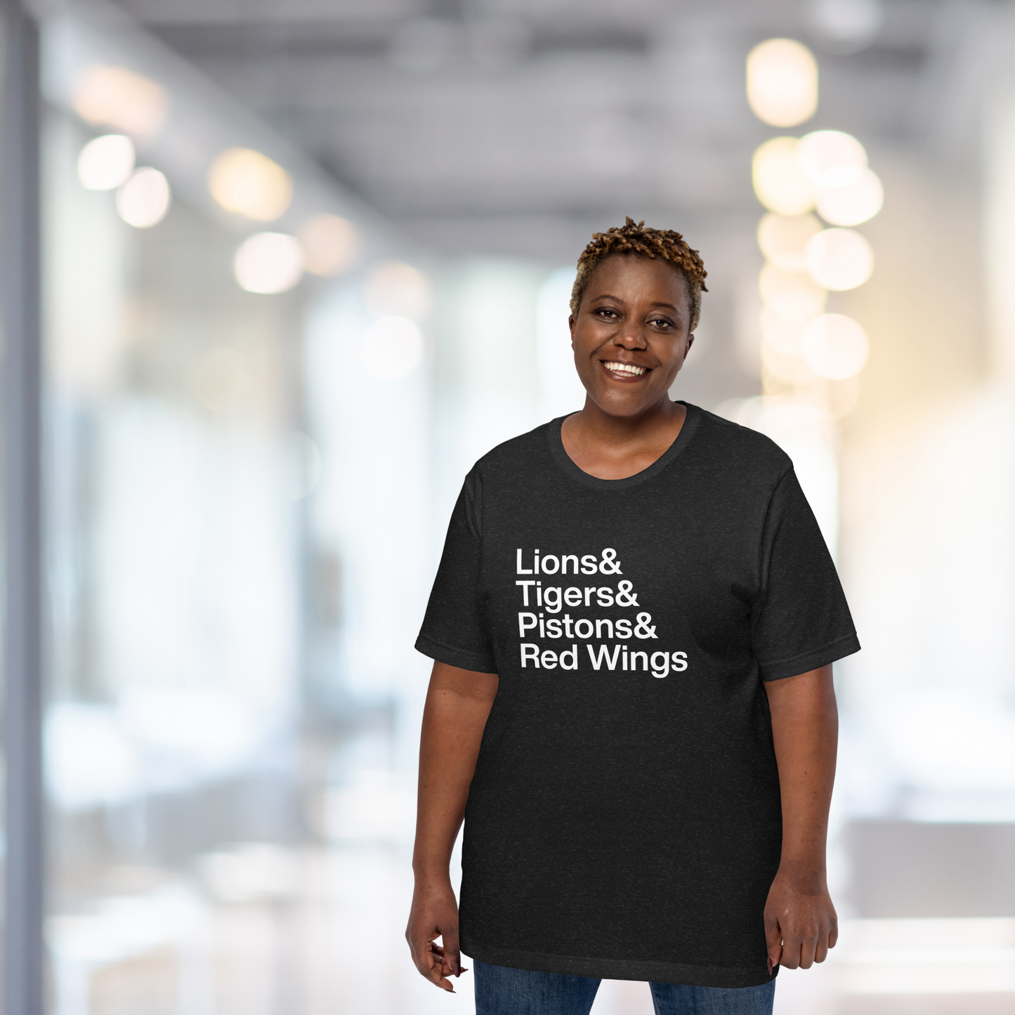 Woman in hallway wearing a black t-shirt which reads Lions and Tigers and Pistons and Red Wings