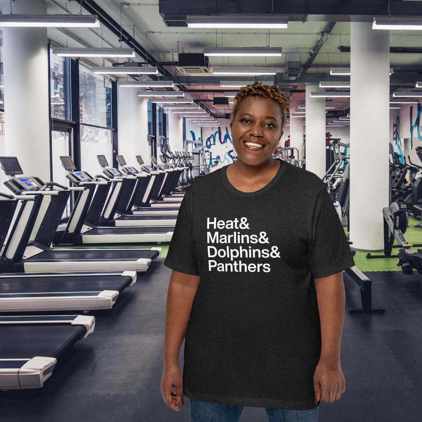 Woman at gym in black t-shirt with white lettering reading Heat and Marlins and Dolphins and Panthers