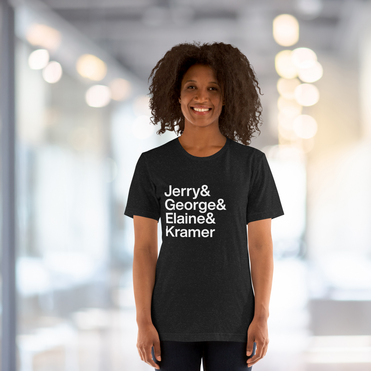 Young lady in hallway wearing black t-shirt with white lettering reading Jerry and George and Elaine and Kramer