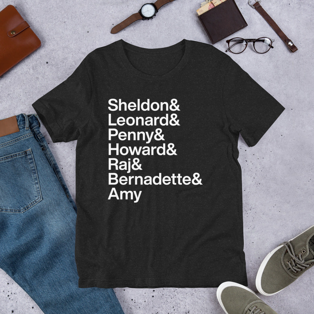 black t-shirt with white lettering reading Sheldon and Leonard and Penny and Howard and Raj and Bernadette and Amy laying on floor amidst other clothing