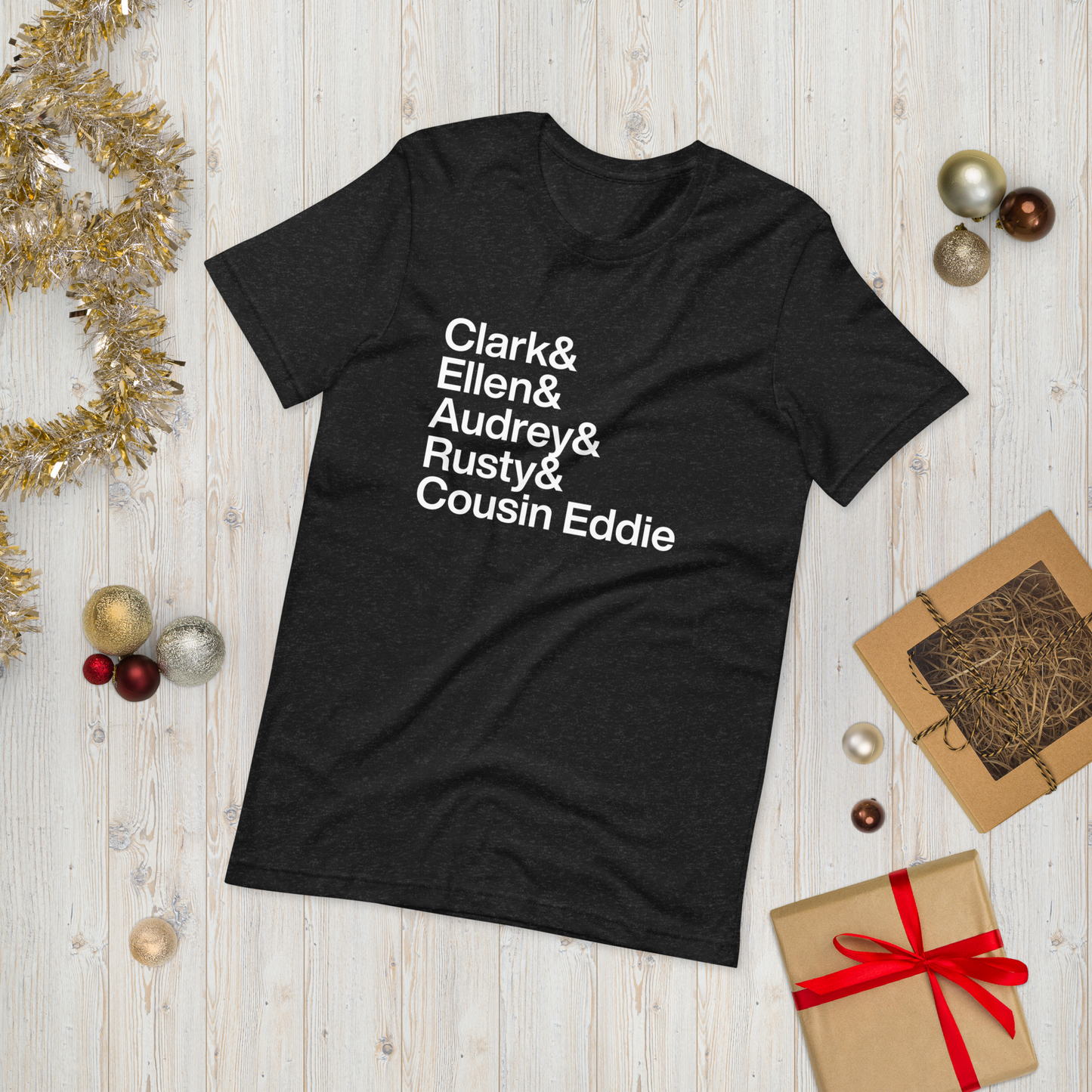 black t-shirt with white text reading Clark and Ellen and Audrey and Rusty and Cousin Eddie on ground amidst other holiday materials